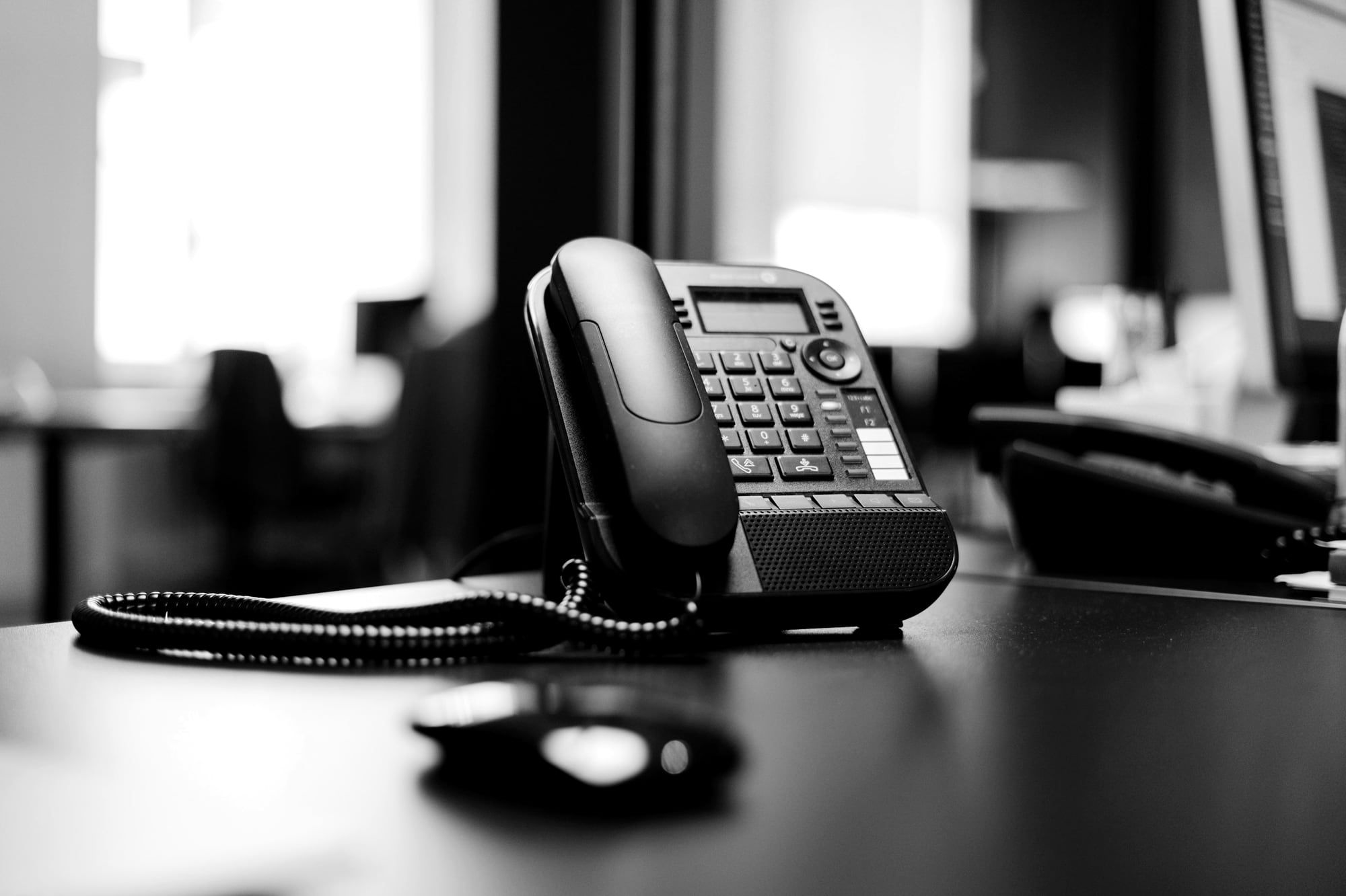 A black desk telephone on a dark table in an office